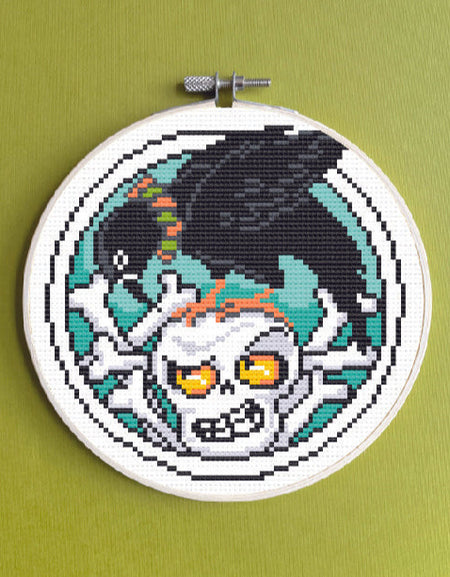 Embroidery hoop with a pixelated skull design on a green background