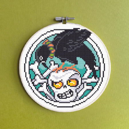 Embroidery hoop with a pixelated skull design on a green background