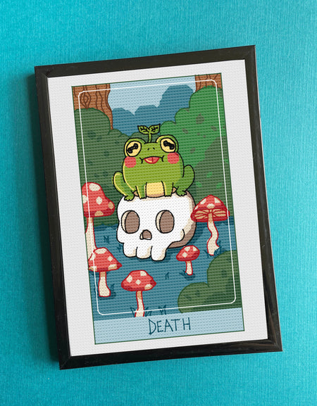 Framed artwork with a cartoon frog on a skull and mushrooms against a blue background