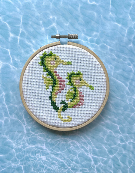 Embroidery hoop with a green seahorse design on a light blue water-like background