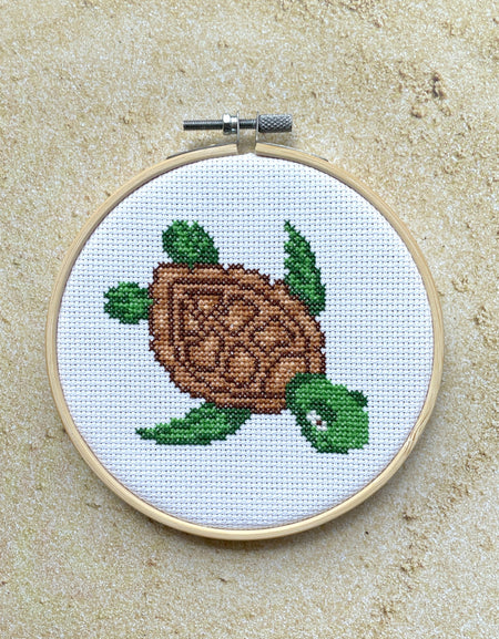Embroidery hoop with a turtle design on a Sand surface