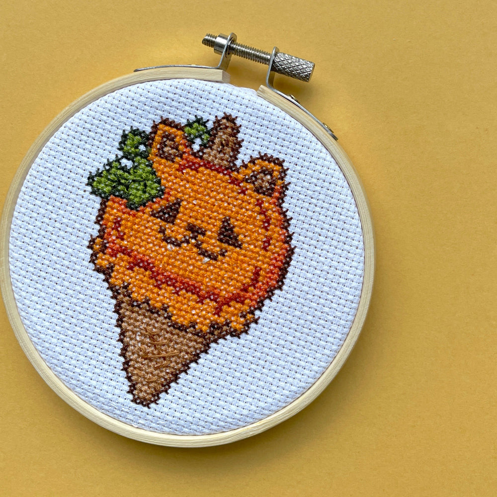 Embroidery hoop with a pumpkin design on a beige background