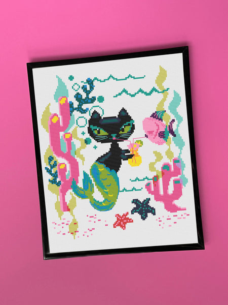 Cross-stitched design of a cat-like creature with sea-themed elements on a pink background
