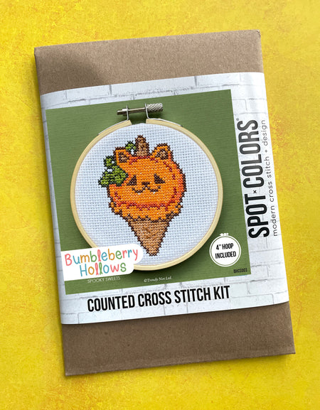 Cross stitch kit packaging with a pumpkin design on a yellow background