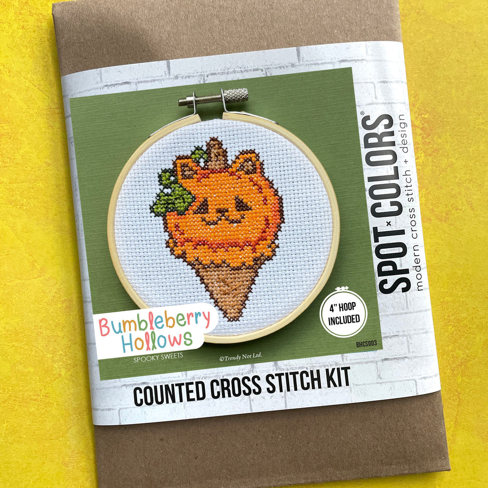Cross stitch kit packaging with a pumpkin design on a yellow background